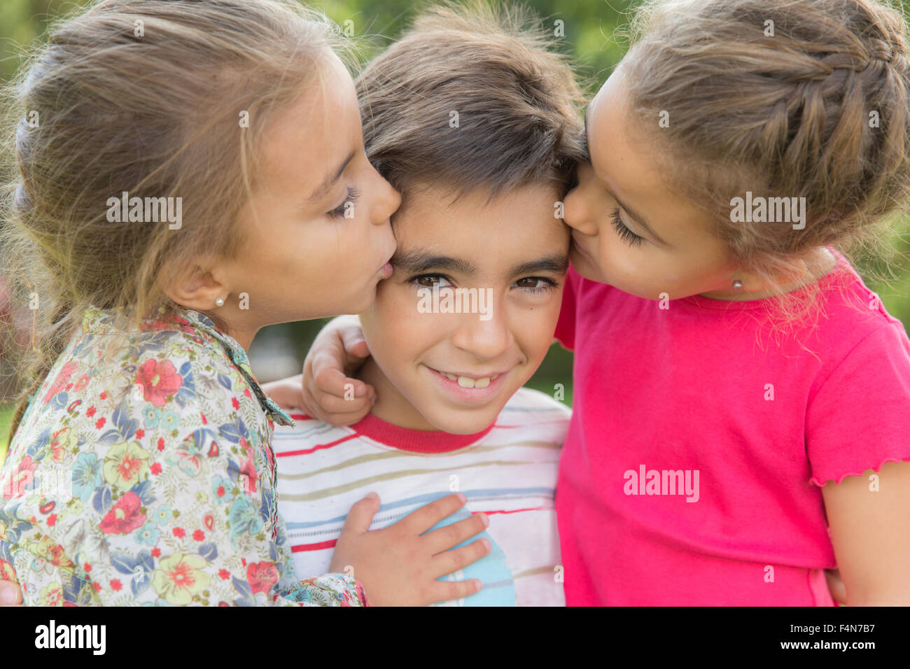 Two little girls kissing a boy Stock Photo