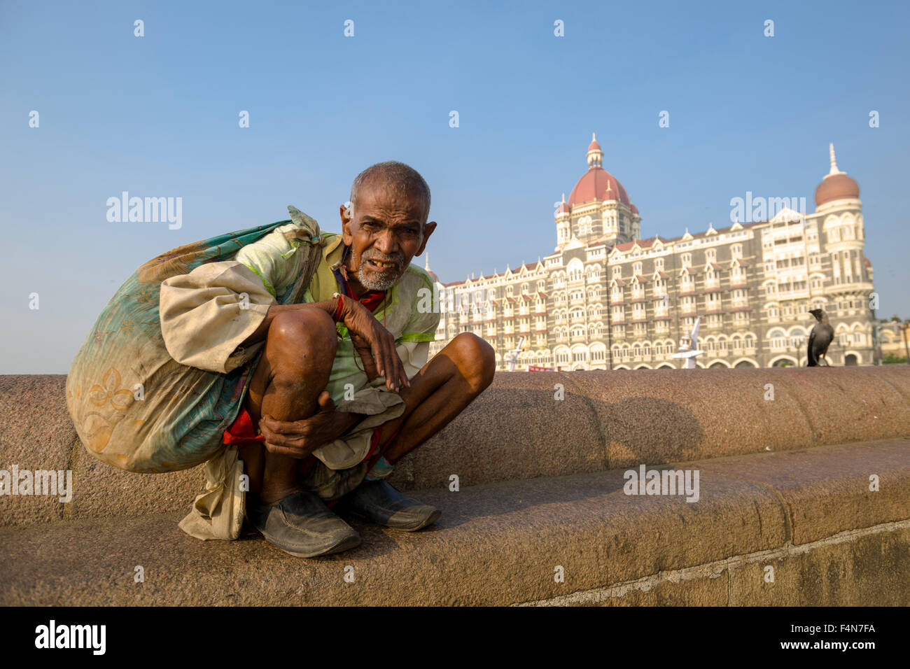 A beggar is sitting in front of the very luxurios and expensive Taj Mahal Palace Hotel in the suburb Colaba Stock Photo