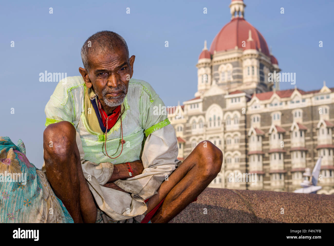 A beggar is sitting in front of the very luxurios and expensive Taj Mahal Palace Hotel in the suburb Colaba Stock Photo