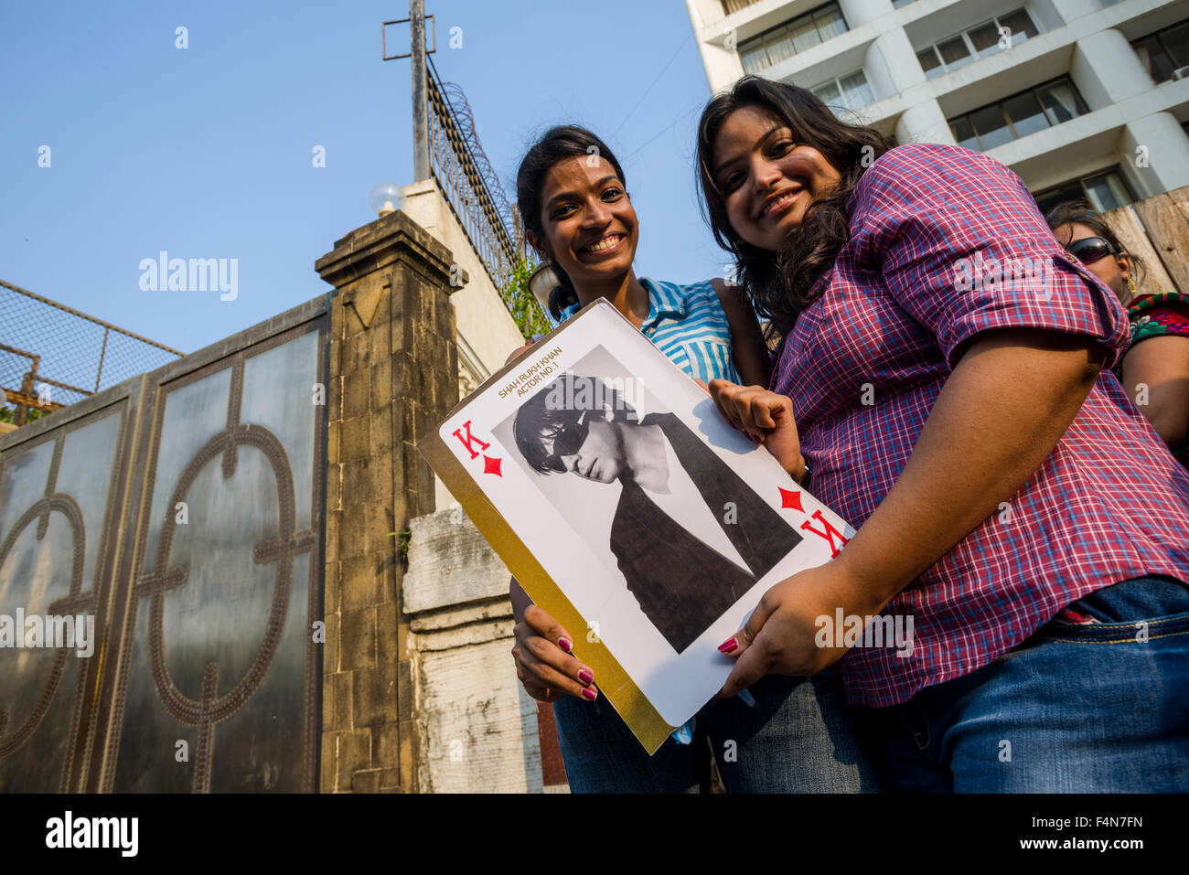 Two young women are displaying a poster of the actor Shahrukh Khan at the gate of his villa at his birthday in the suburb Bandra Stock Photo