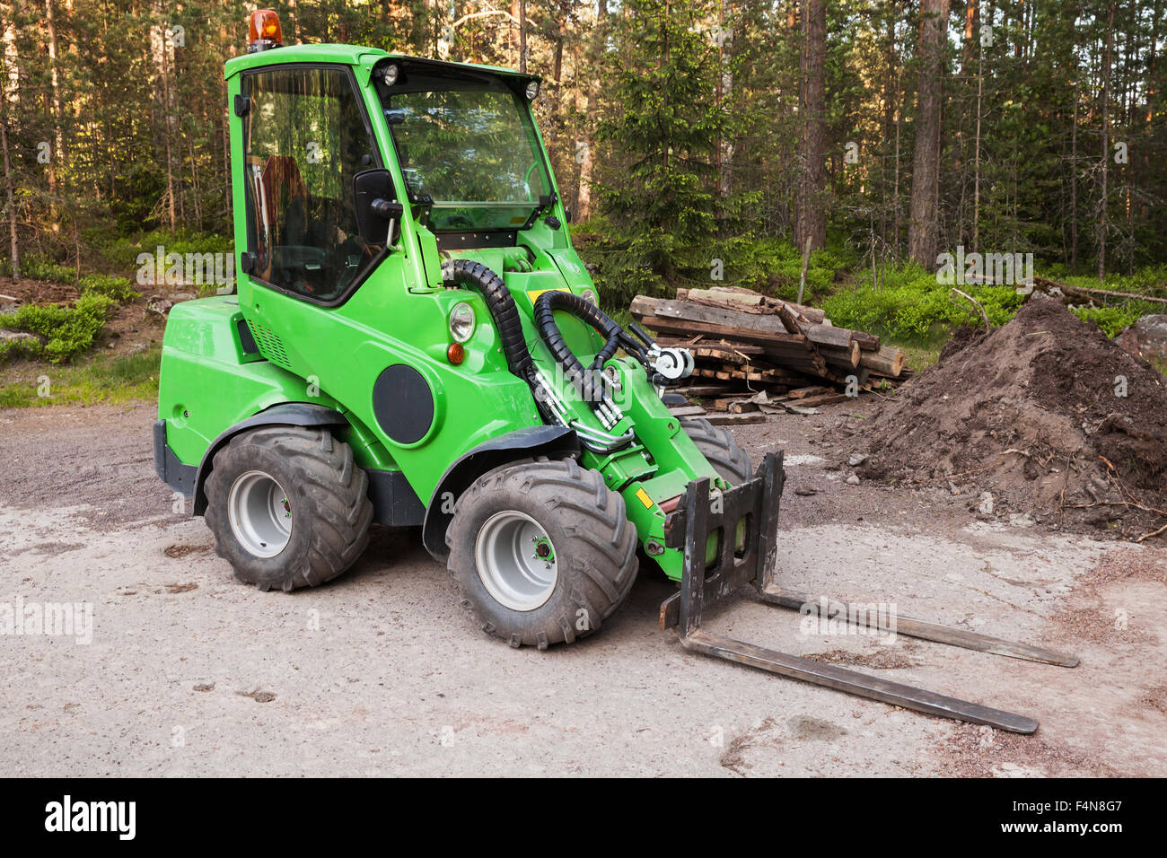 Green small forklift stands on a logging area in forest Stock Photo