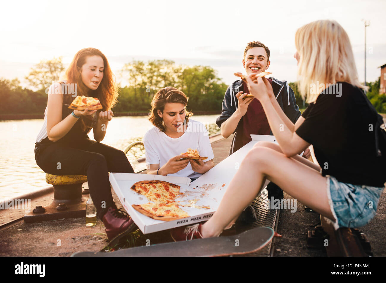 Friends sitting together outdoors sharing a pizza Stock Photo