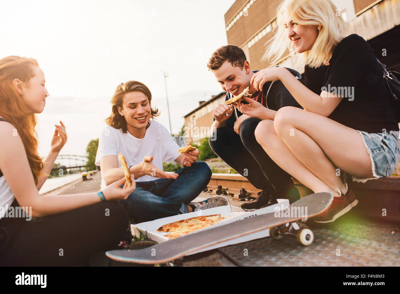 Friends sitting together outdoors sharing a pizza Stock Photo