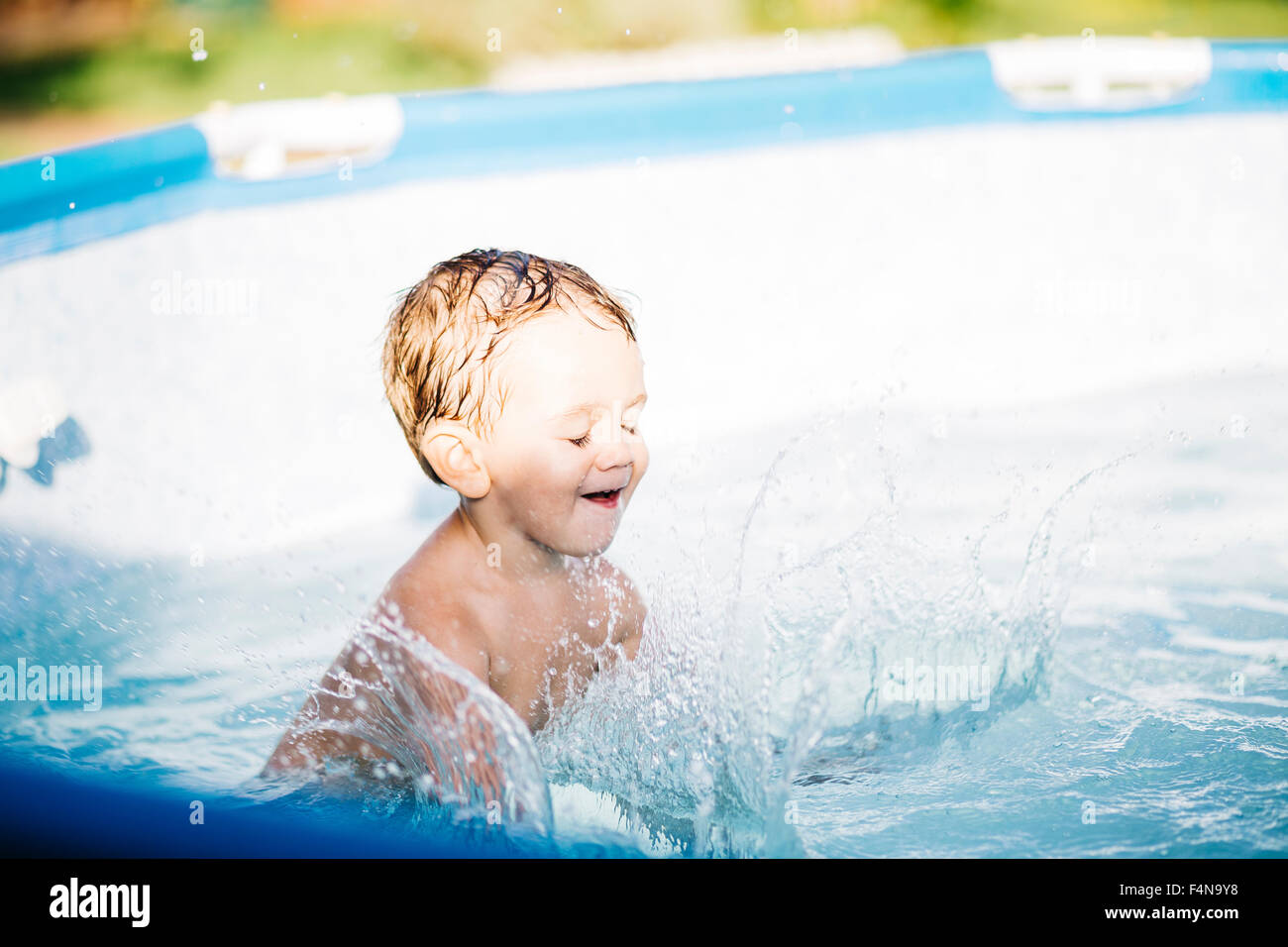 Little boy splashing in a paddling pool Stock Photo Alamy