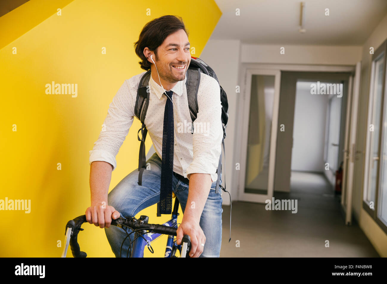 Portrait of smiling man with racing bicycle in a corridor Stock Photo