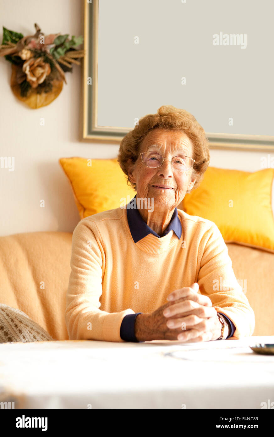 Portrait of aged woman sitting on couch in her living room Stock Photo ...