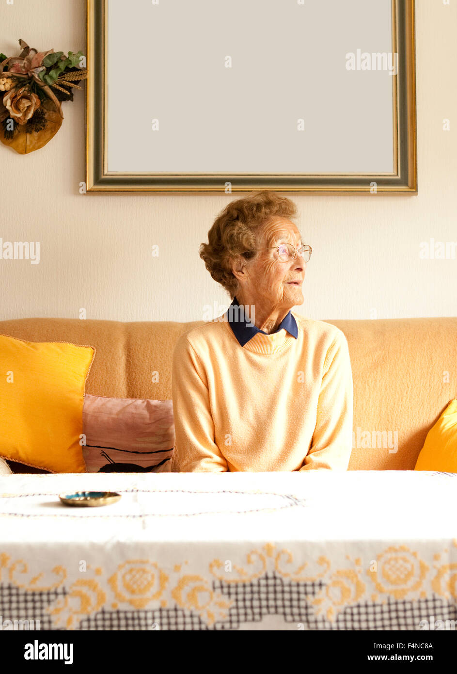 Portrait of aged woman sitting on couch in her living room Stock Photo ...