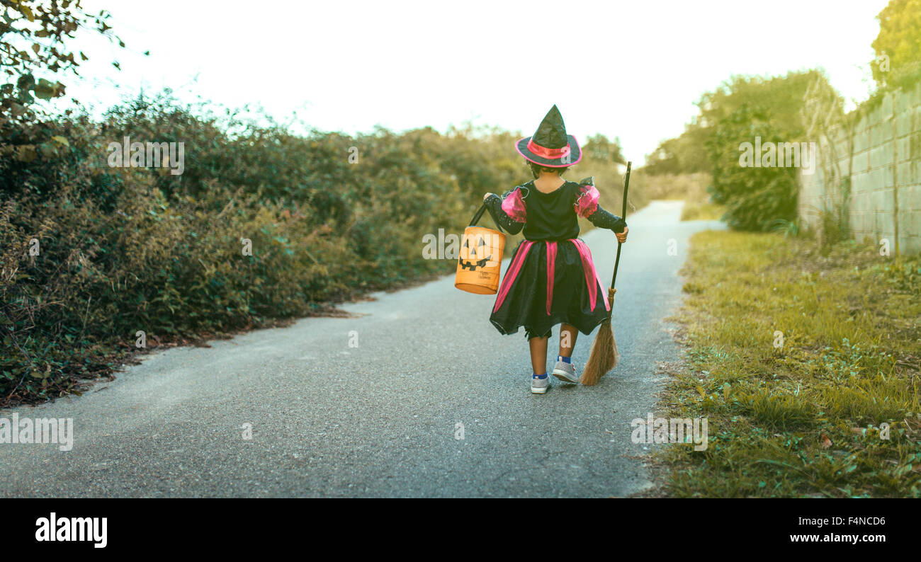 Back view of little girl masquerade as a witch with halloween lantern ...