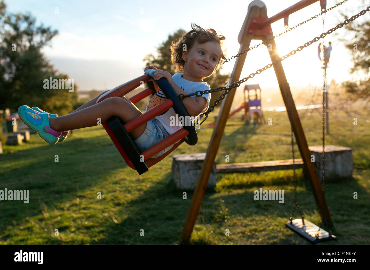 Portrait of happy little girl on a swing at backlight Stock Photo - Alamy