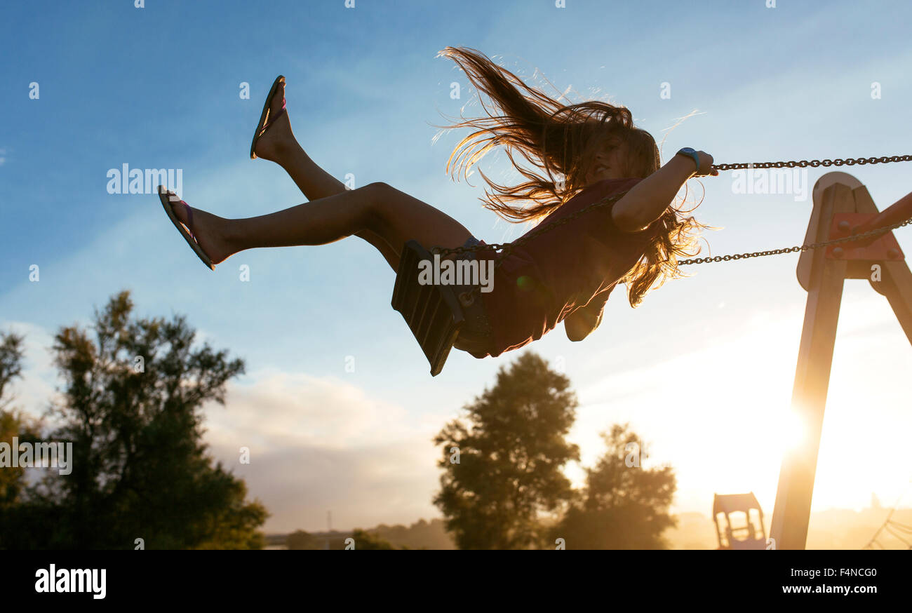 Girl with blowing hair on a swing at backlight Stock Photo - Alamy