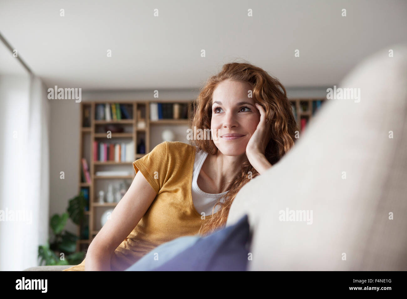 Smiling woman at home sitting on couch Stock Photo - Alamy