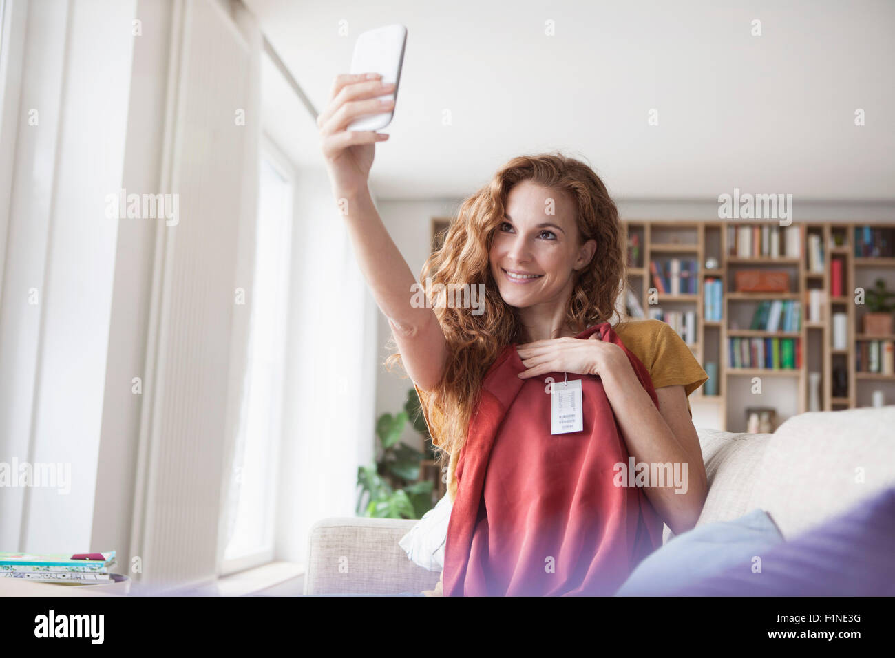 Smiling woman at home taking a selfie with new garment Stock Photo