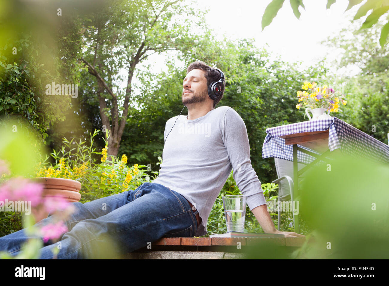 Relaxed man sitting in garden with headphones Stock Photo