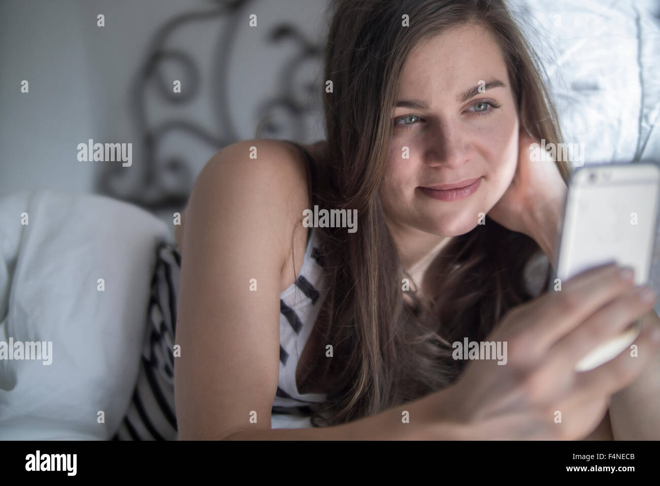 Young woman lying in bed, taking selfie with smart phone Stock Photo