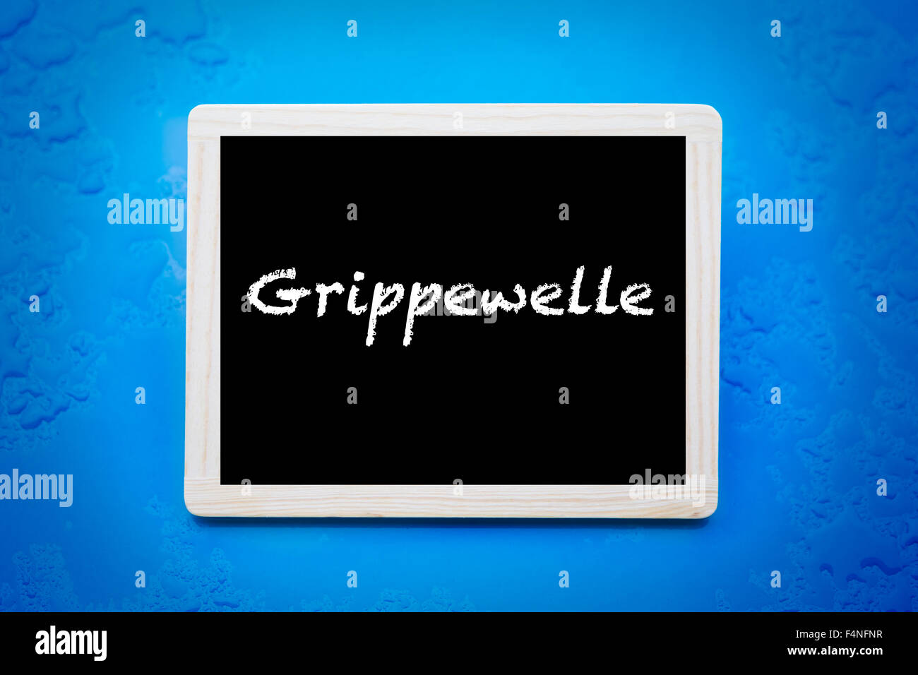 blackboard with german word 'Grippewelle' (flu season) on blue wet background Stock Photo