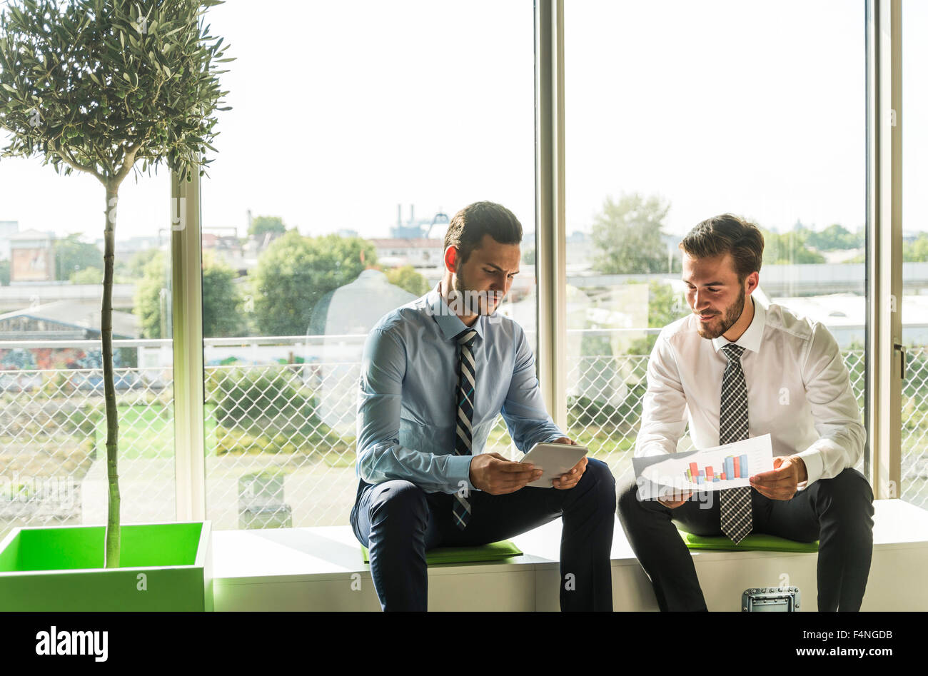 Two young businessmen looking at document and digital tablet Stock Photo
