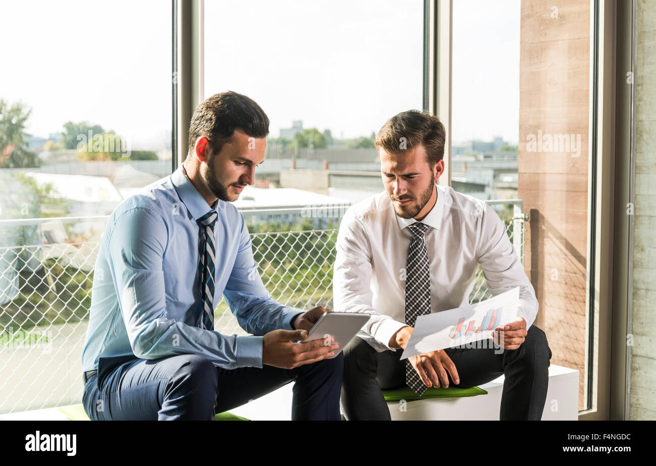 Two young businessmen looking at document and digital tablet Stock Photo