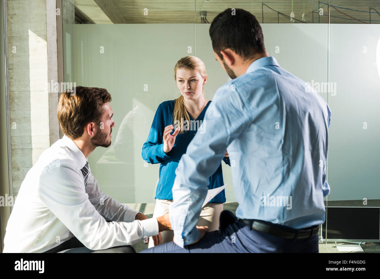 Three young business people discussing in office Stock Photo - Alamy