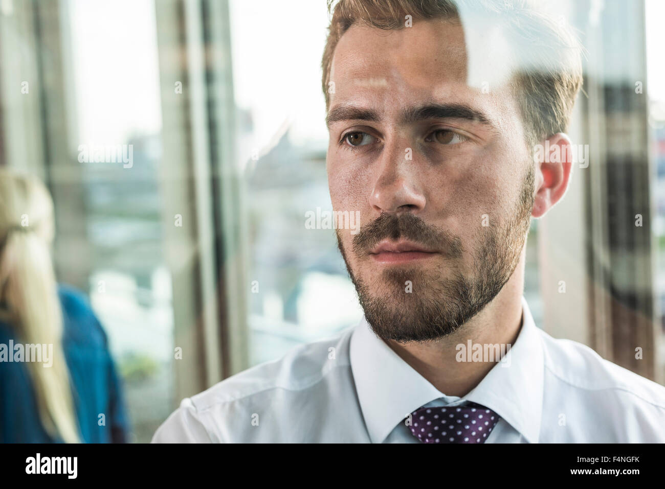 Serious young businessman looking out of window Stock Photo