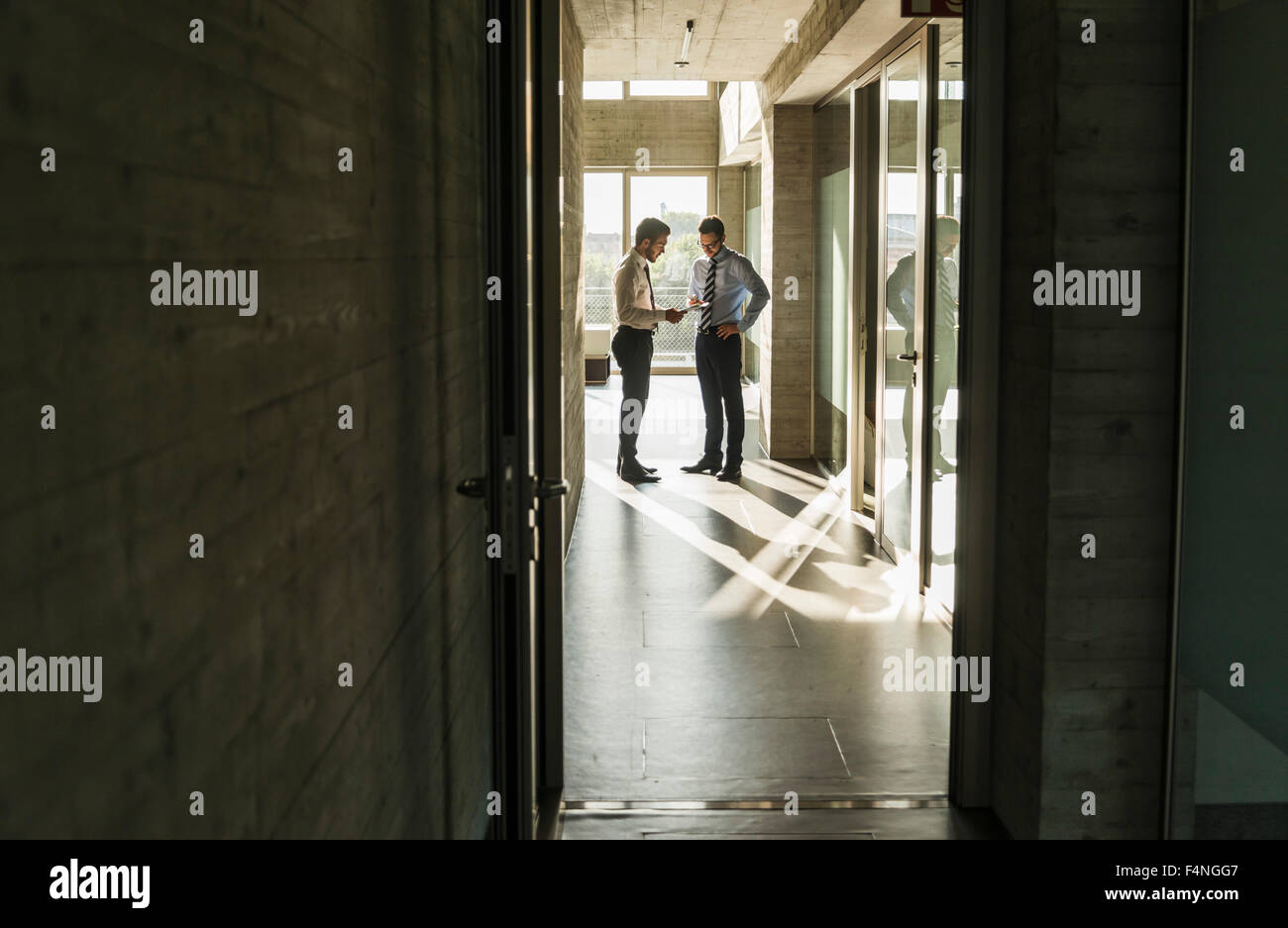 Two businessmen standing in office hall Stock Photo - Alamy