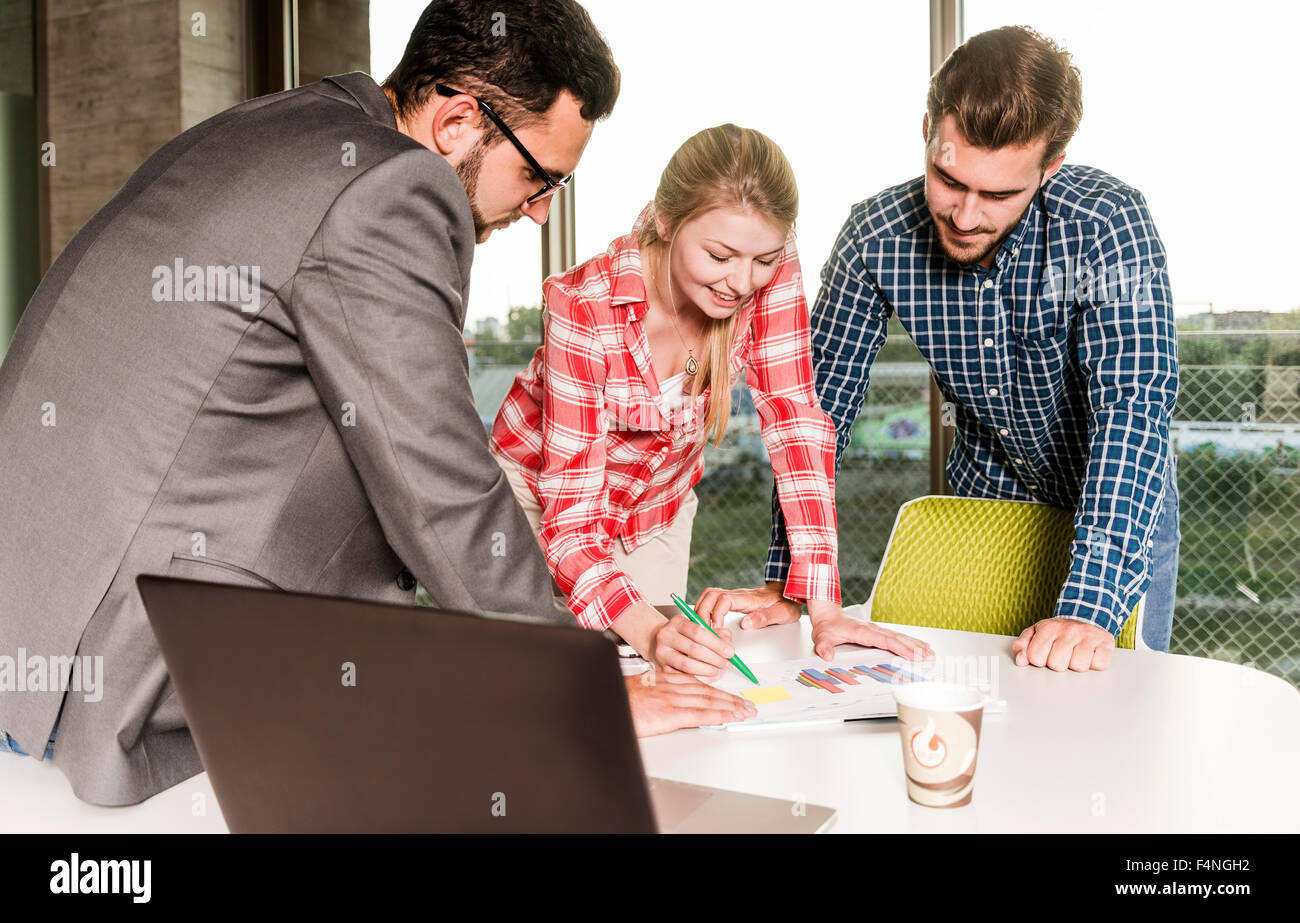 Three young people in conference room working at diagram Stock Photo