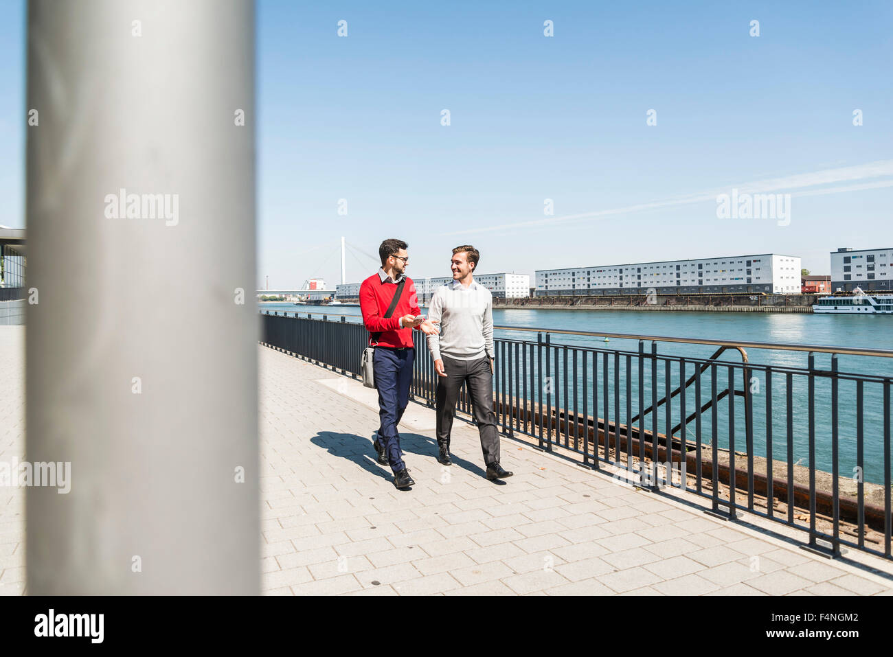 Two young businessmen walking by the riverside Stock Photo - Alamy