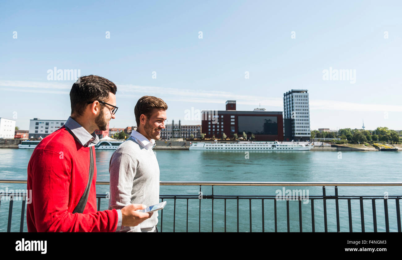 Two young businessmen walking by the riverside Stock Photo