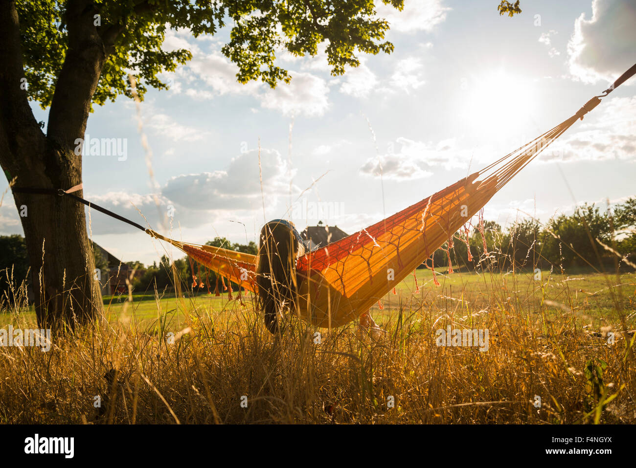 Back view of woman with headphones lying in a hammock relaxing in nature Stock Photo
