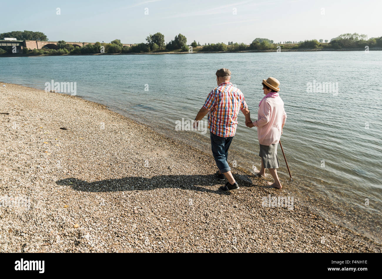 Germany, Ludwigshafen, senior couple walking hand in hand at riverside Stock Photo