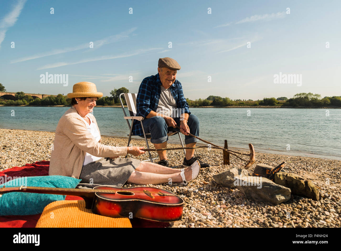 Germany, Ludwigshafen, senior couple barbecueing sausages on the beach Stock Photo