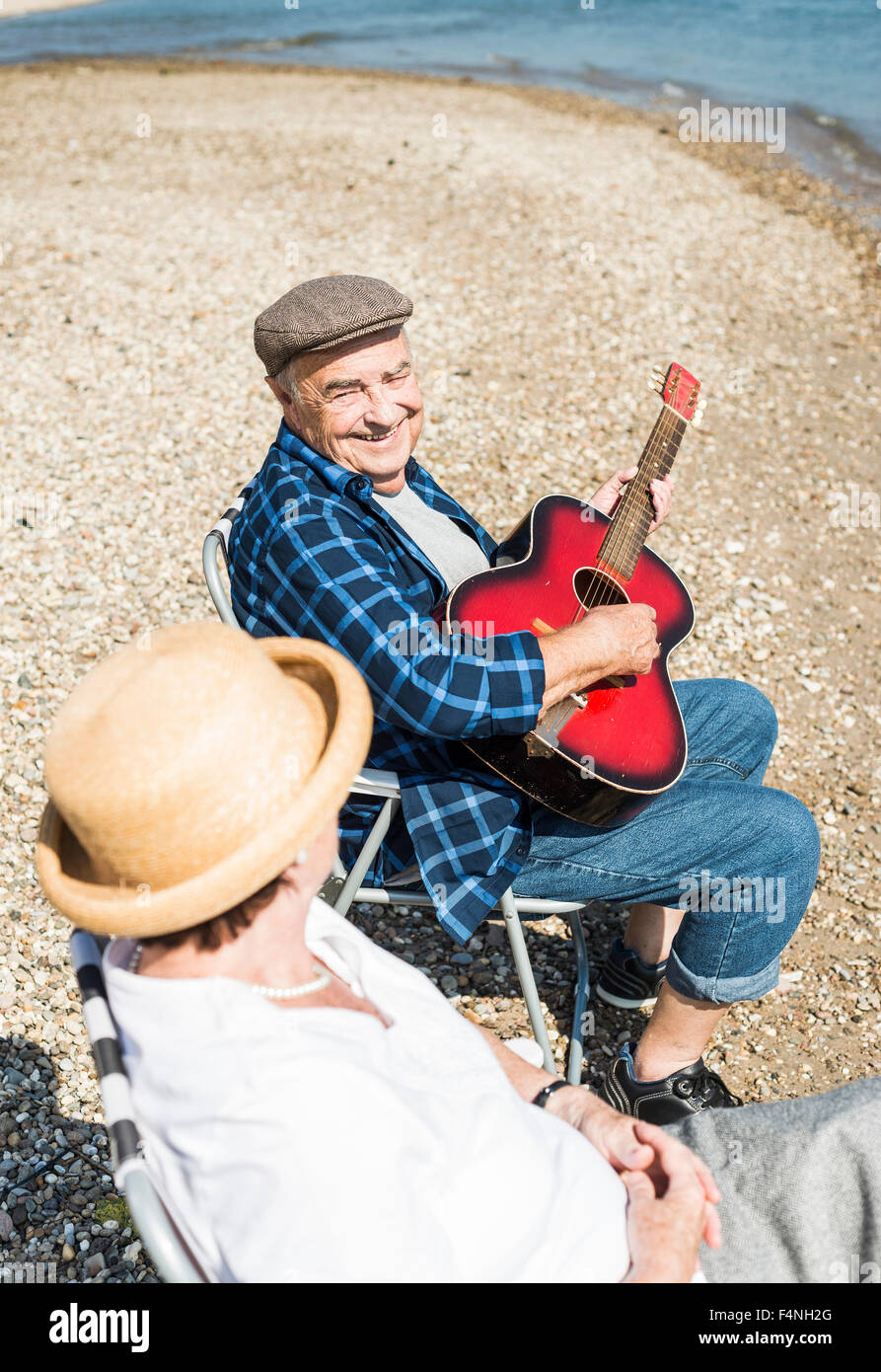 Germany, Ludwigshafen, portrait of smiling senior man with guitar besides his wife at riverside Stock Photo