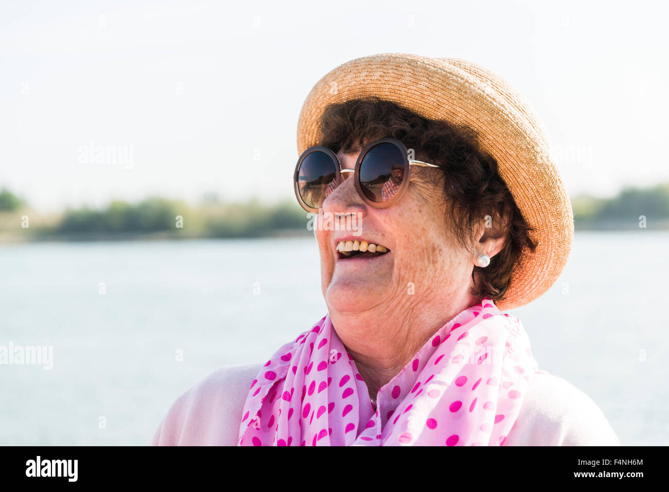 Portrait of smiling senior woman wearing sunglasses and summer hat ...