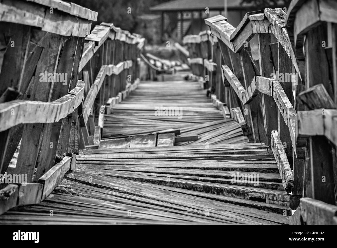 Closeup of a deformed and dilapidated wooden bridge in black and white Stock Photo