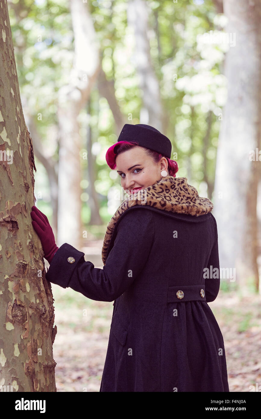 Portrait of fashionable young woman with coloured hair viewing over her shoulder in the woods Stock Photo