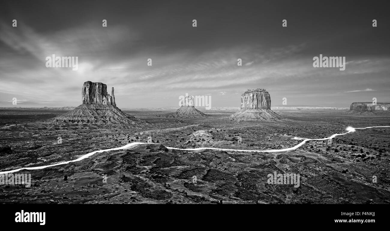 Black and white photo of the Monument Valley with car lights trails at night, USA. Stock Photo