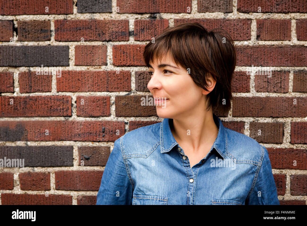 Woman leaning against a brick wall Stock Photo - Alamy