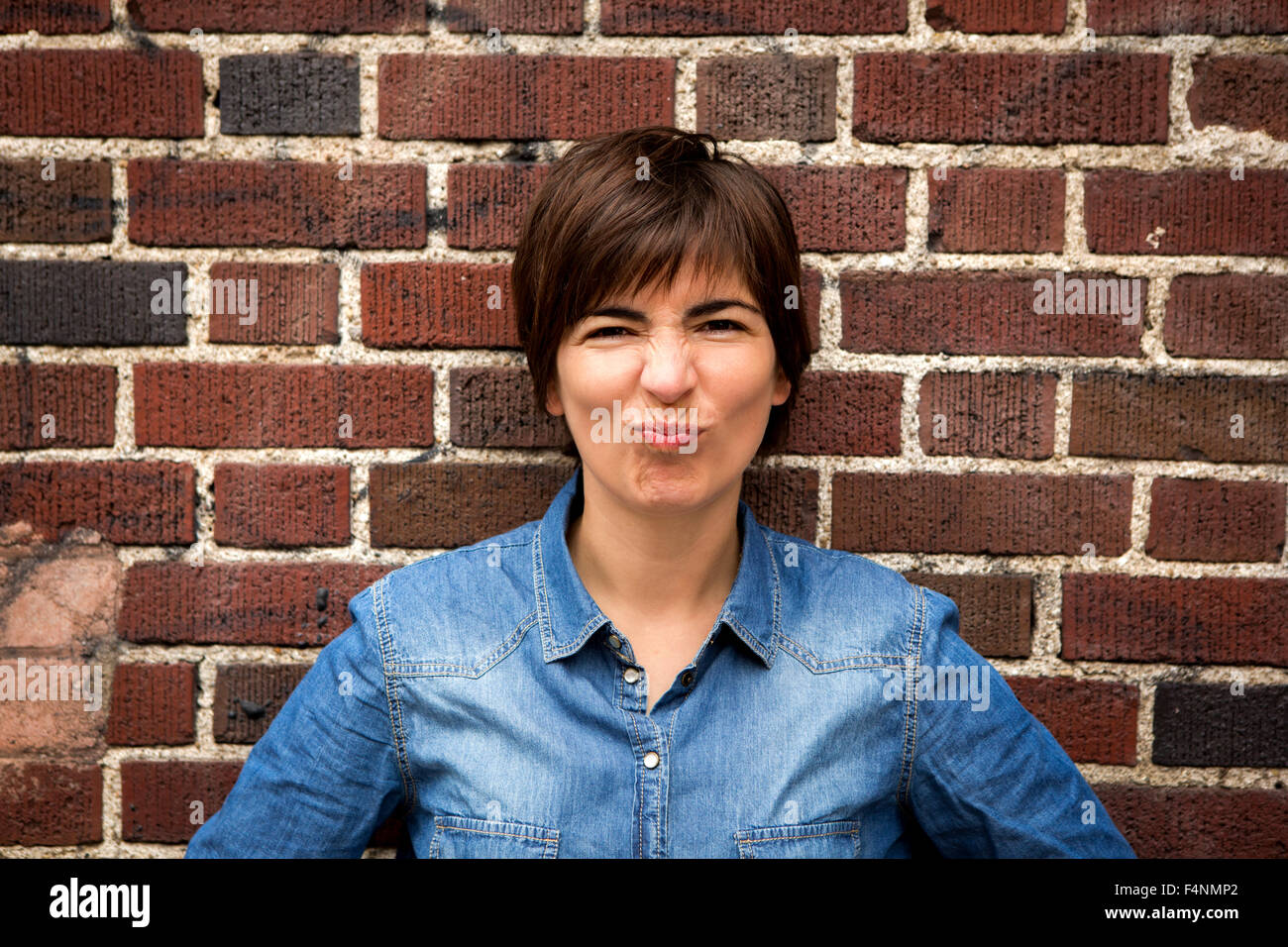 Woman leaning against a brick wall Stock Photo - Alamy