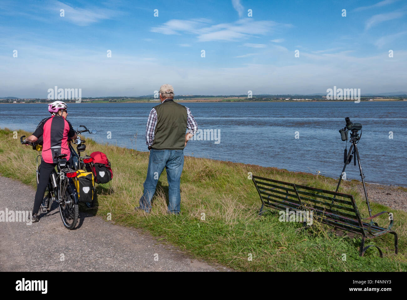 Cyclist on the Hadrian's Cycleway NCN 72] stops for a chat with a local birdwatcher by the Solway Firth Stock Photo