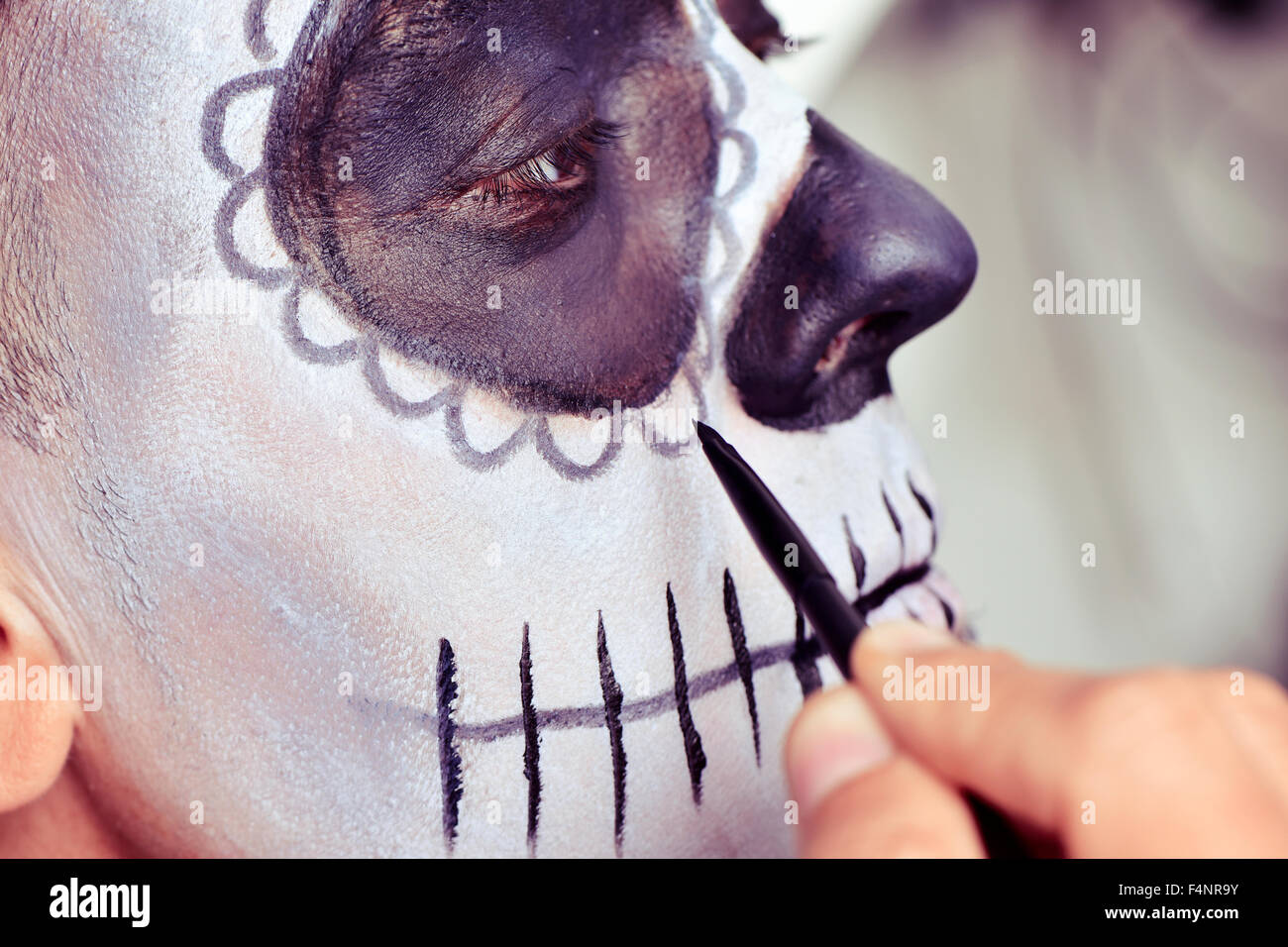 closeup of a young man making up himself as a mexican sugar skull Stock Photo
