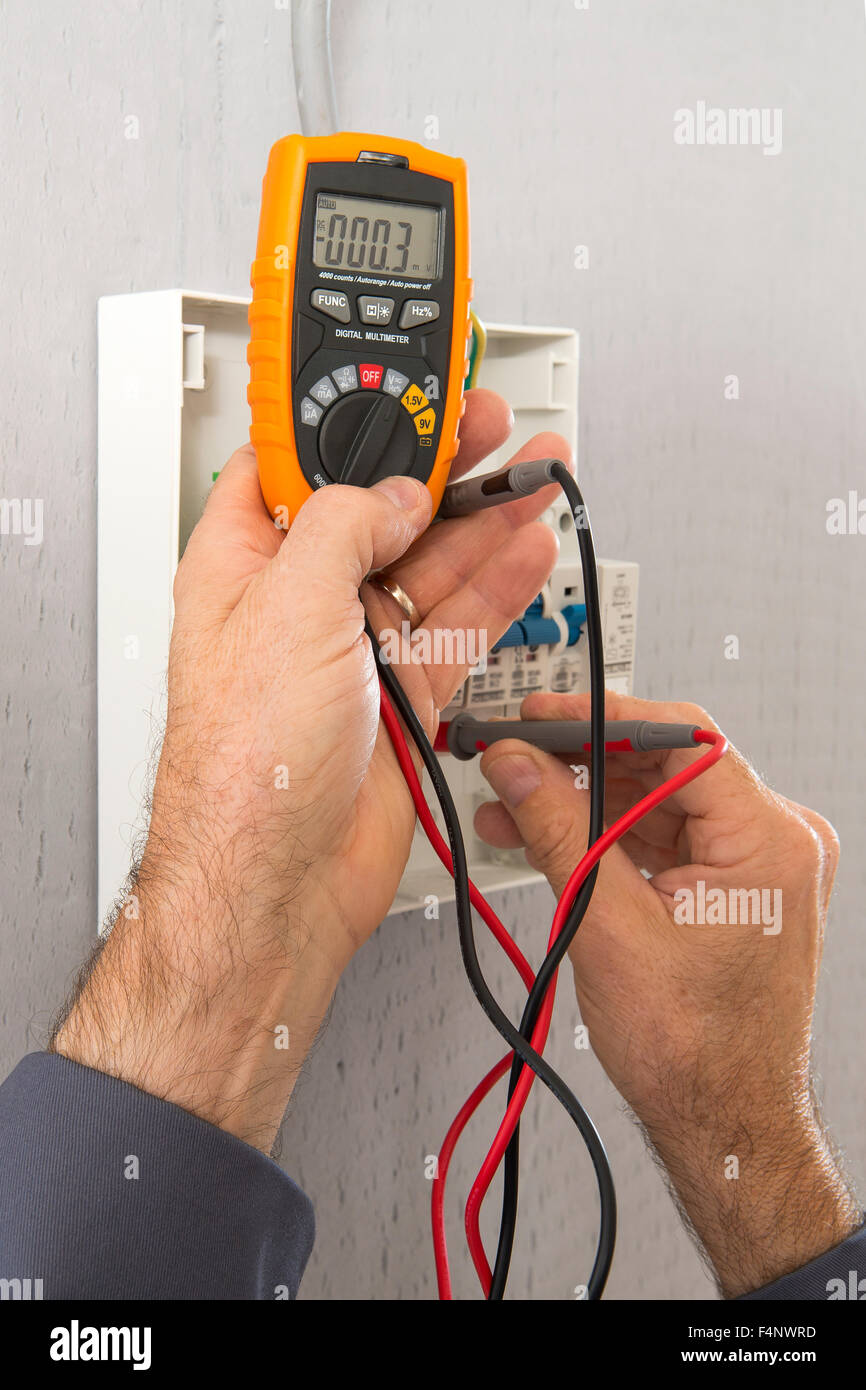 Hand of an electrician with multimeter probe at an electrical