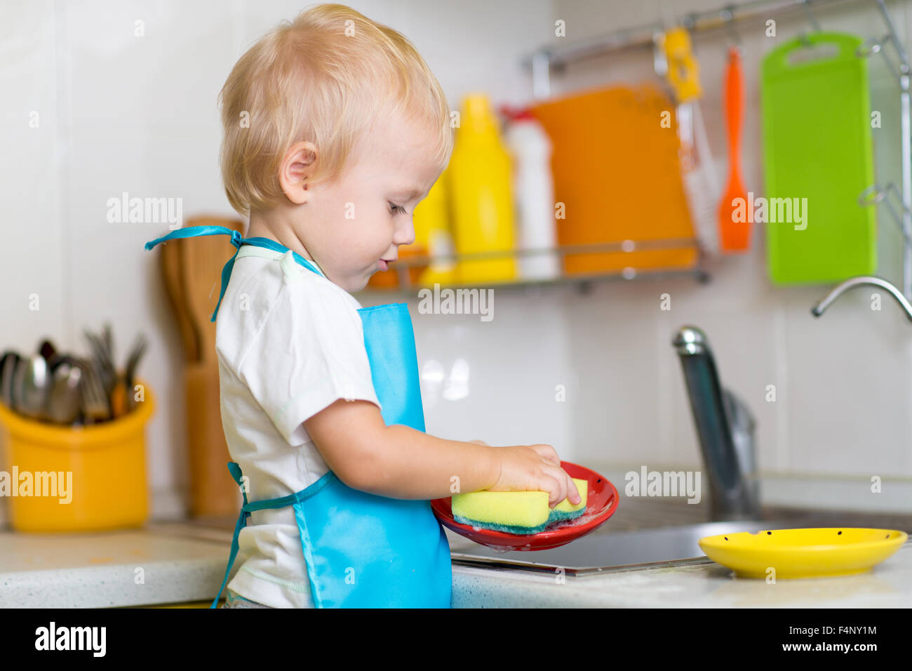 Child washing dishes in a domestic kitchen Stock Photo