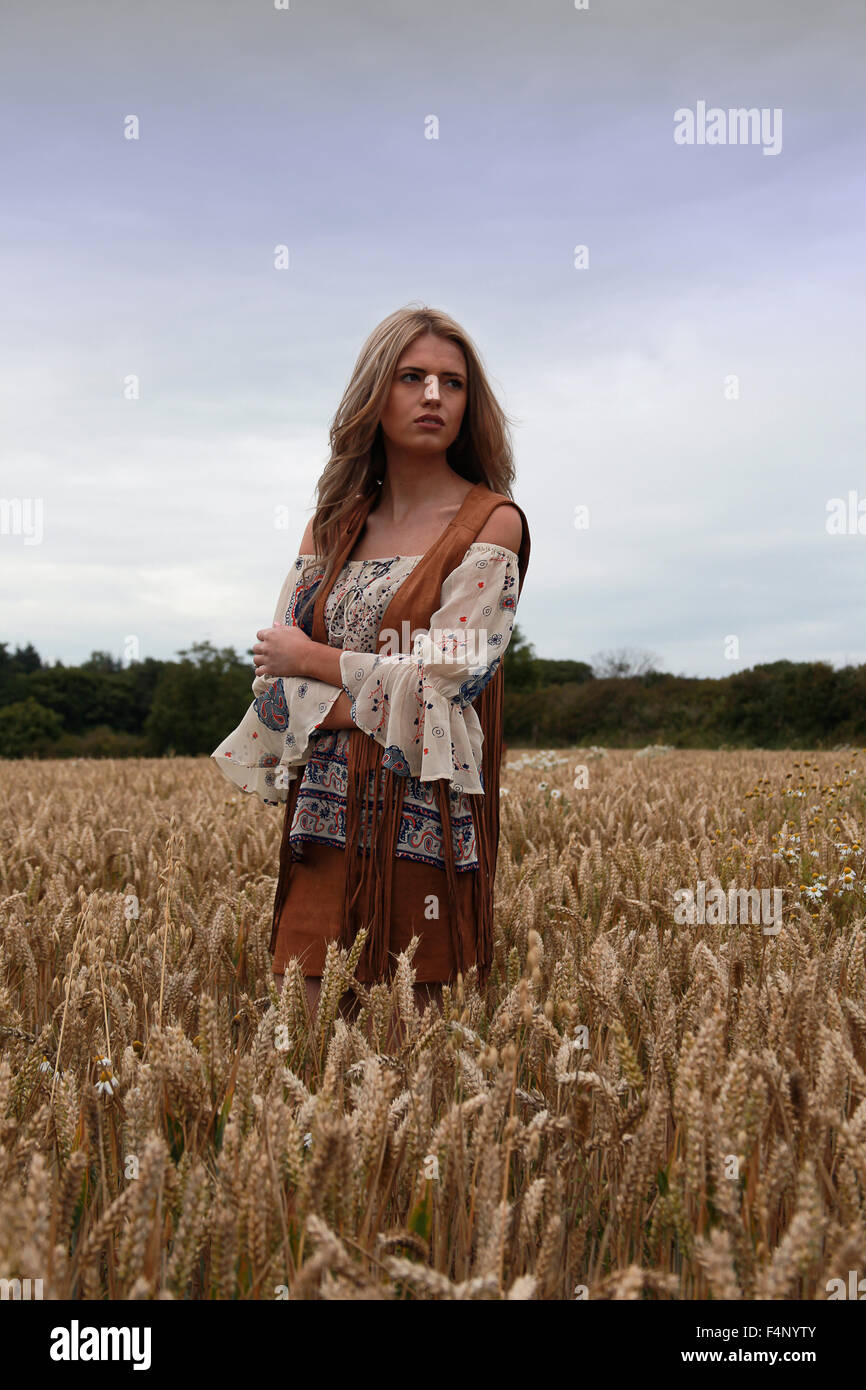 Beautiful teenage girl standing in a meadow looking sad with dramatic moody sky Stock Photo