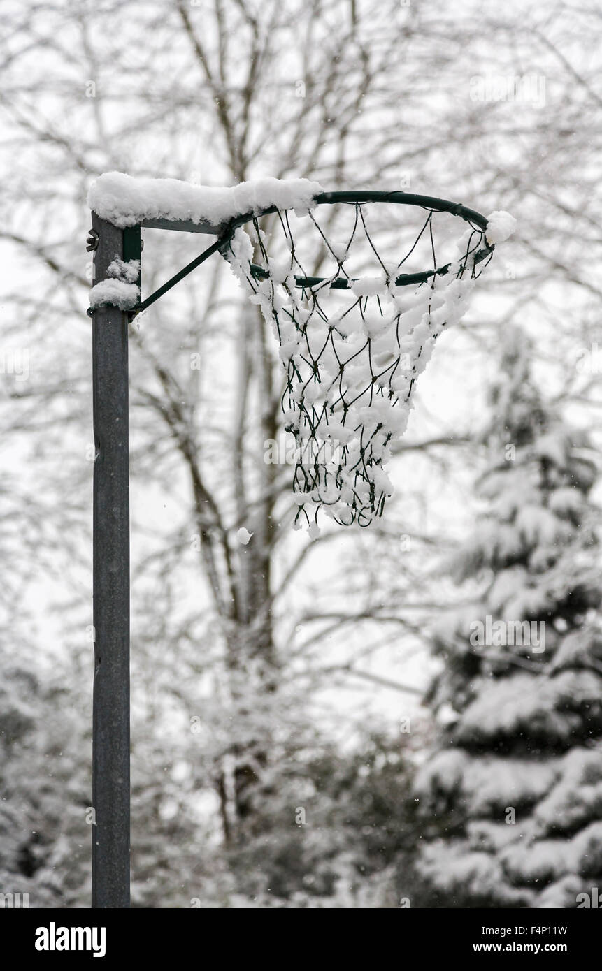 Netball goalpost with a covering of snow on a cold, dull winter day with almost monochromatic appearance, Surrey, southeast England, UK Stock Photo