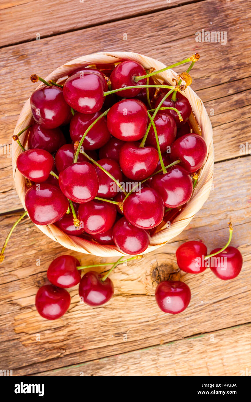 Fresh cherries in basket on wooden table. Stock Photo