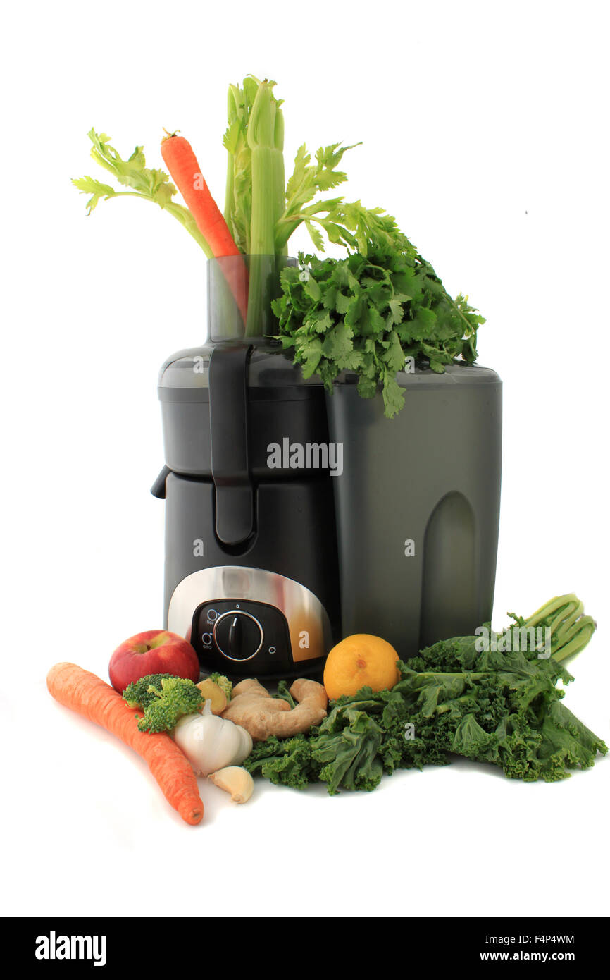 Juicer surrounded by healthy vegetables like carrots, ginger, and kale ready to make  fresh  juice Stock Photo