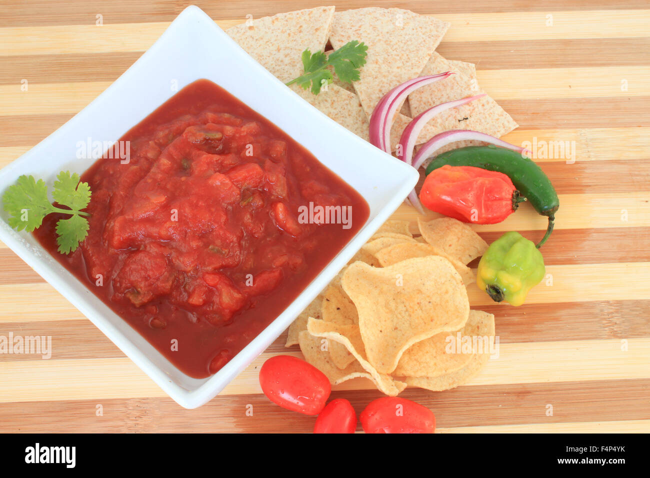 Bowl of tomato salsa with hot spicy peppers like jalapenos, onions, chips and tortillas for dipping Stock Photo