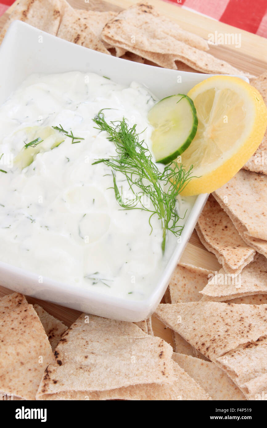 Tzatziki sauce made with yogurt, cucumbers, dill and lemon in a bowl with pita chips on the side