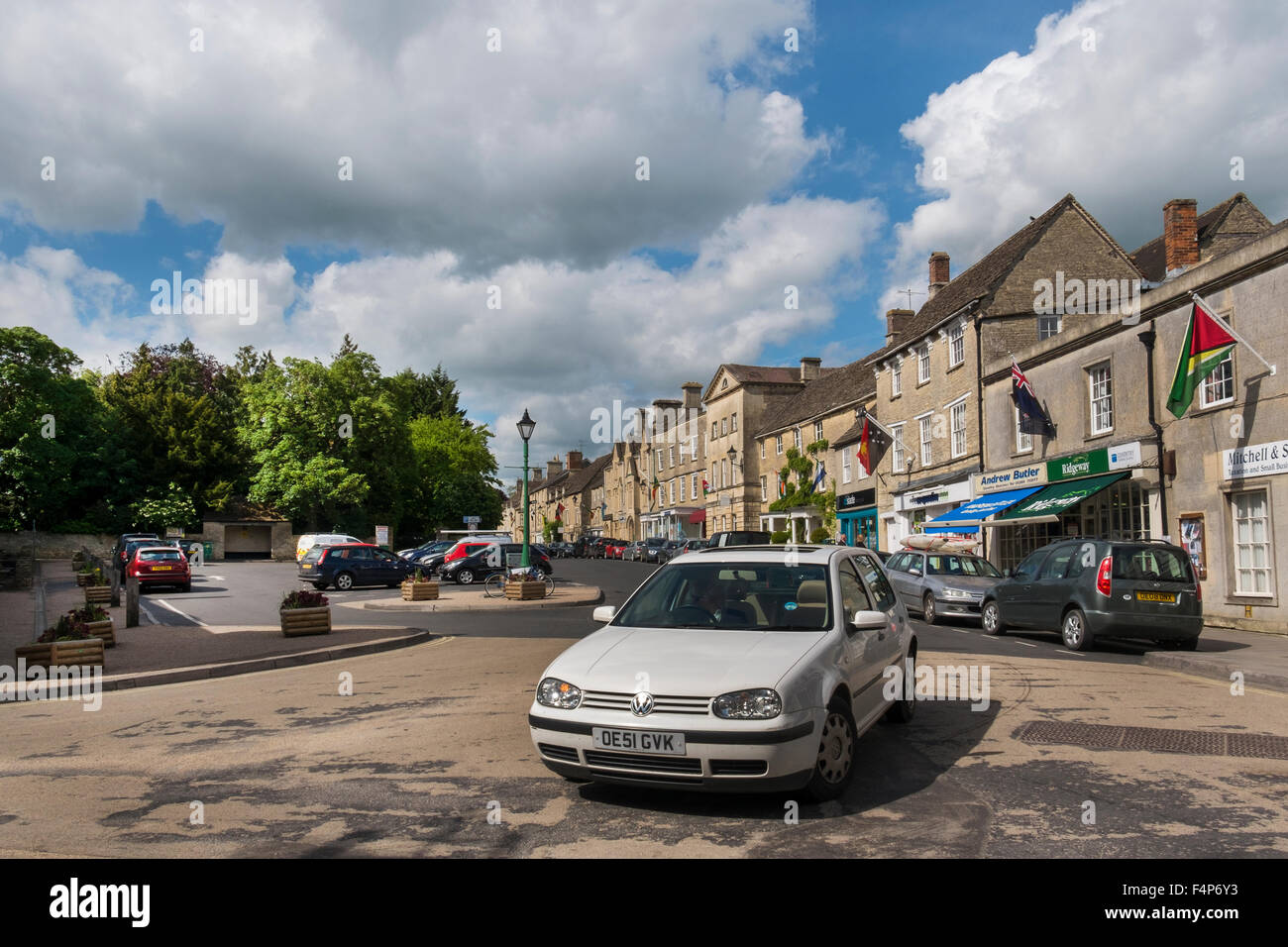 A VW Golf driving out of the Market Square in the High Street, Fairford, Gloucestershire, UK Stock Photo