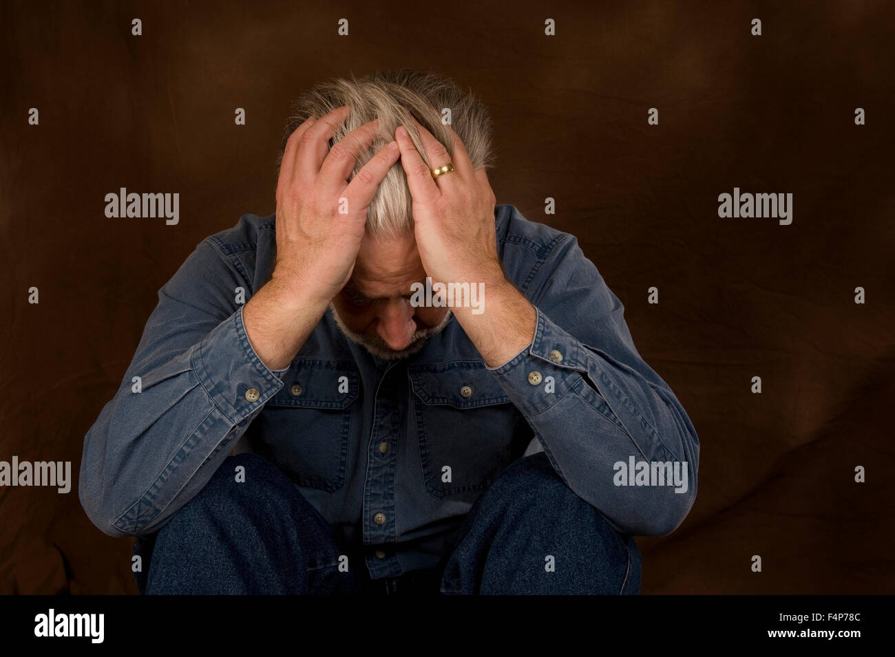 A mature man holds his head in his hands showing he is In Despair on a ...
