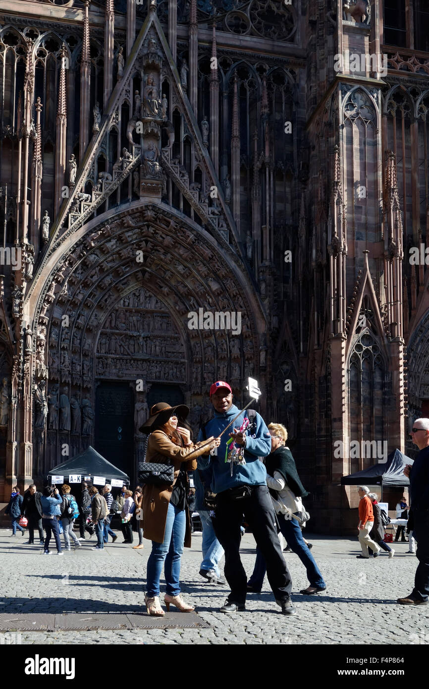 Tourist with camera on selfie stick in front of Cathedral of Our Lady of Strasbourg, Alsace, France Stock Photo